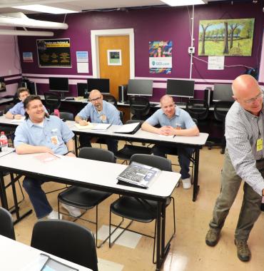 Instructor writes on whiteboard in front of students